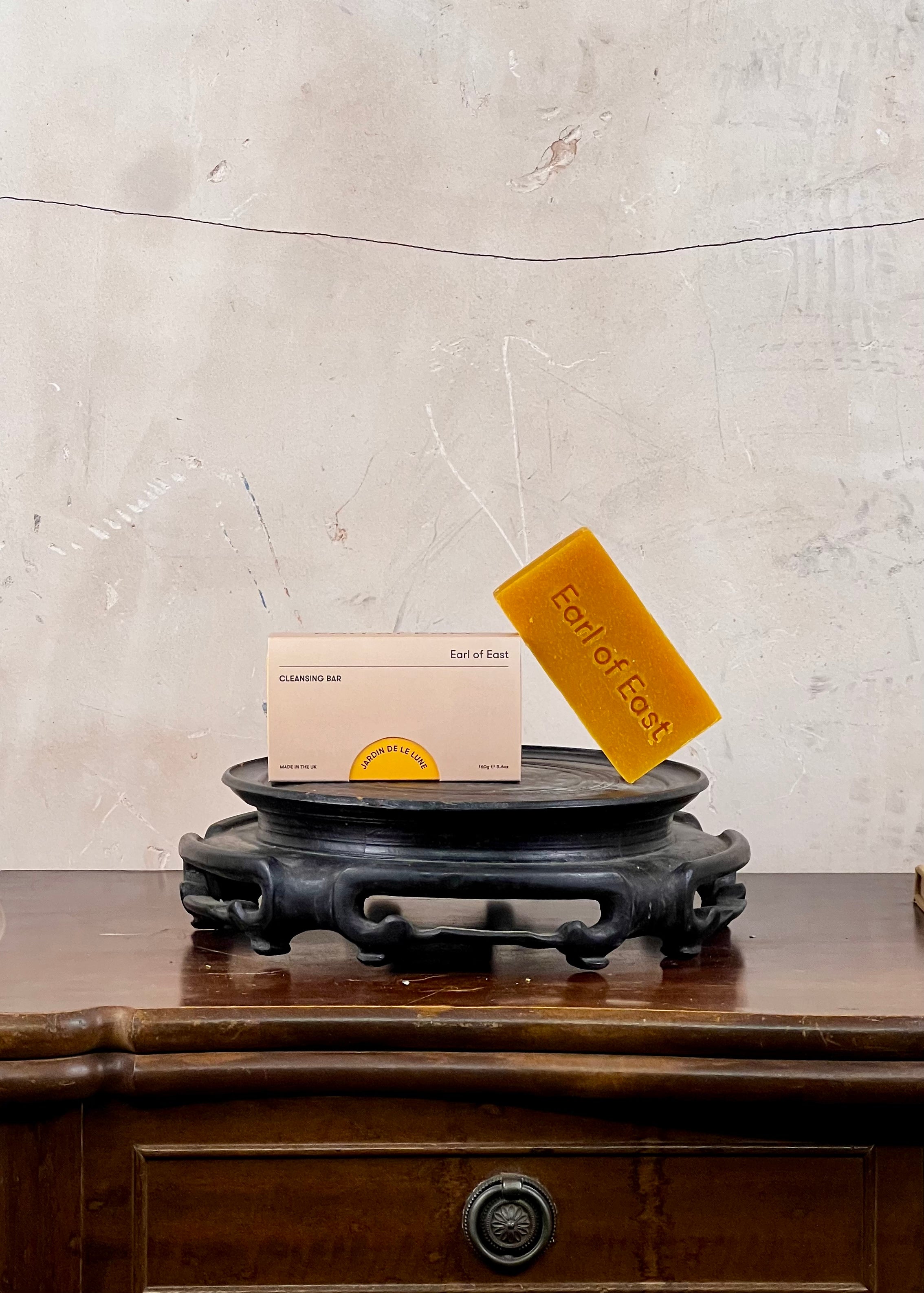 Two bars of soap on a wooden stand with a textured wall background
