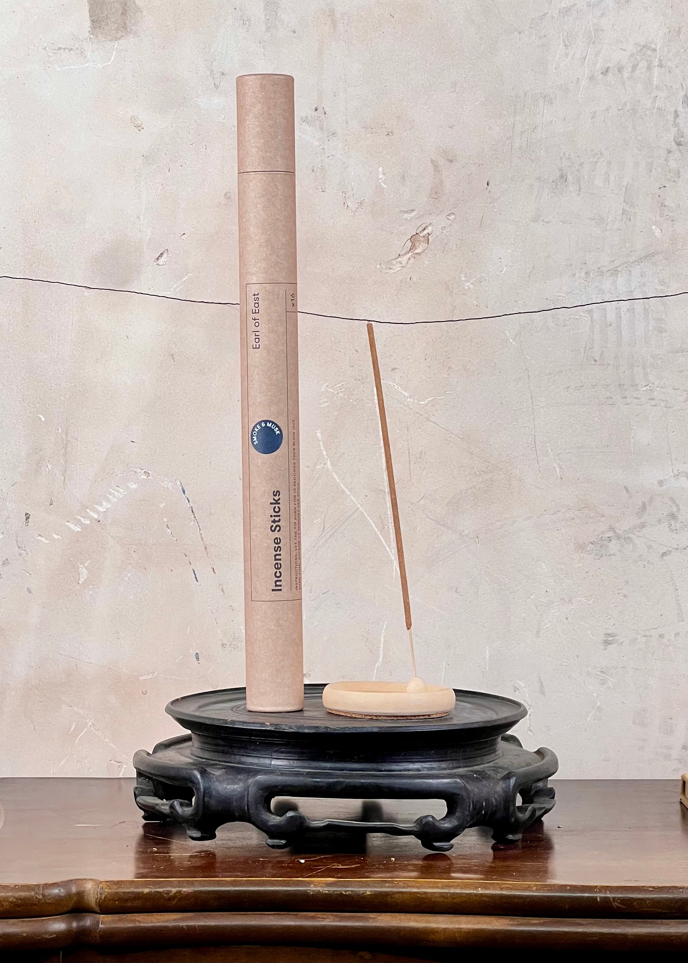 Incense stick holder with a cylindrical incense stick on a textured surface