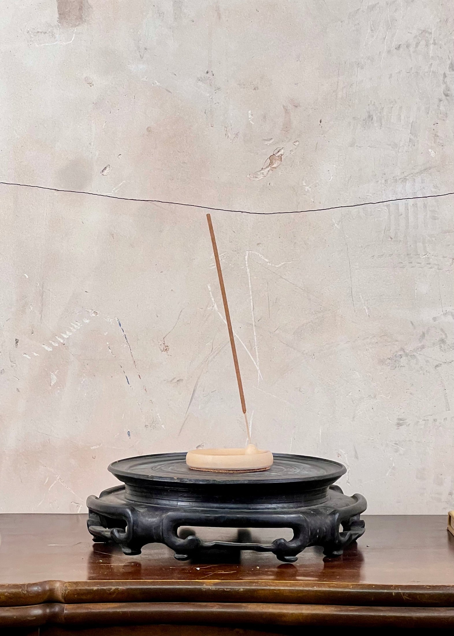 Incense stick on a small round stone platform with a textured wall background