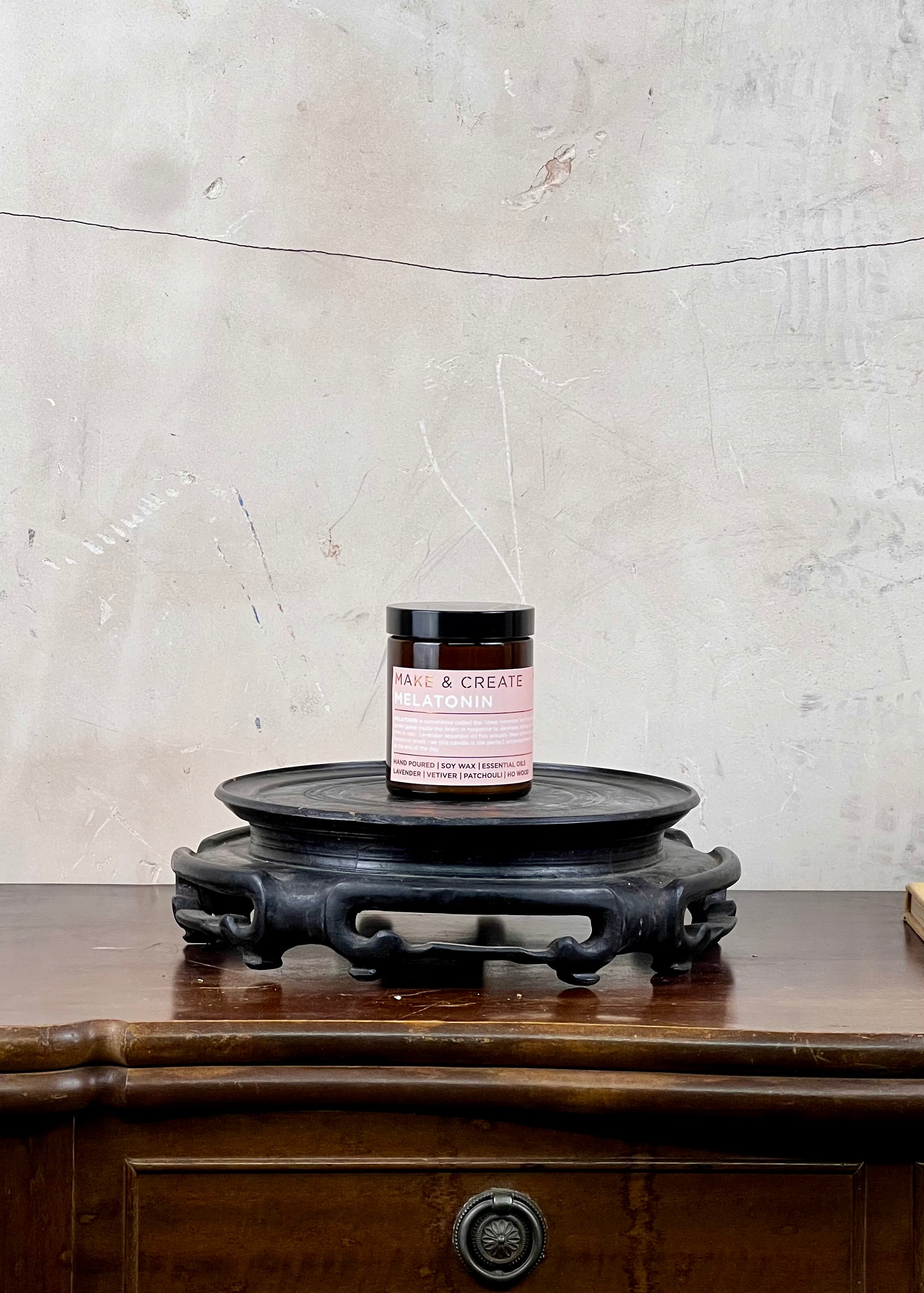 A soy wax candle jar on a wooden surface with a textured wall background