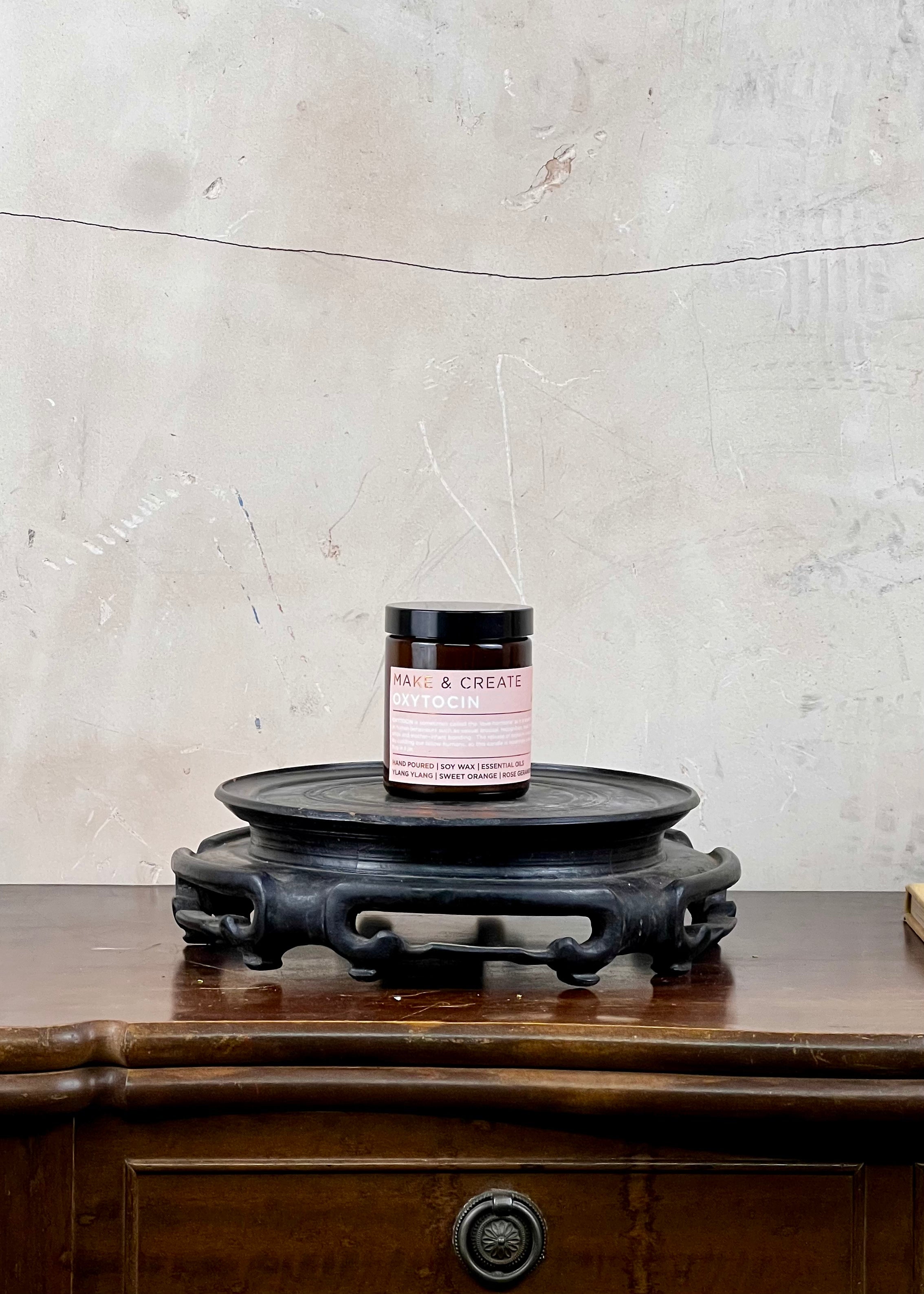 A soy wax candle jar on a wooden surface with a textured wall background
